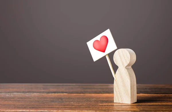 Un hombre con un corazón rojo a la señal. Búsqueda activa de un socio para citas. Simpatía y amor, expreso apoyo, como. Celebrando el Día de San Valentín. Citas en línea, construcción de relaciones. Dar preferencia —  Fotos de Stock