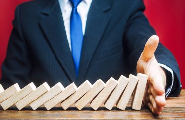 İşadamı Domino 'nun avucunun içine düşmesini engelliyor. Risk yönetimi konsepti. Başarılı, güçlü bir iş ve problem çözme. Yıkıcı işlemleri durdurun. Strateji geliştirme. Borç yeniden yapılandırması