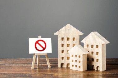 Figures of residential buildings and red prohibition sign no. Inaccessible and expensive housing. Seizure and freezing of assets by a bank, court. Restrictions and a ban on the construction of housing clipart