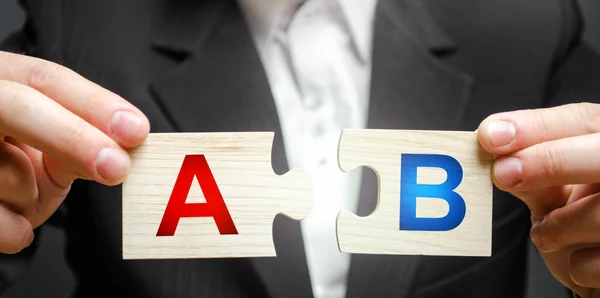 Een man verbindt puzzels met de letters A en B. A/B test marketing onderzoeksmethode. Multivariate testen. Het verbeteren van producten en diensten op basis van statistieken en observaties. Marketeer — Stockfoto