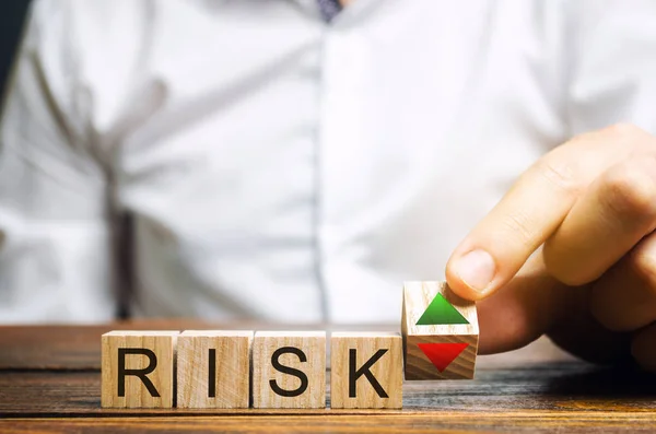 İşadamı "Risk" ve "yukarı ve aşağı" okları olan tahta bloklar koyar. İş risk yönetimi konsepti. Tahmin ve planlama. Risk değerlendirmesi ve sigorta — Stok fotoğraf