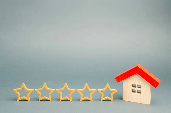 Five stars and a wooden house on a gray background. The concept of the best housing, luxury apartments VIP class. The best service and universal recognition, a high evaluation. Success. Feedback