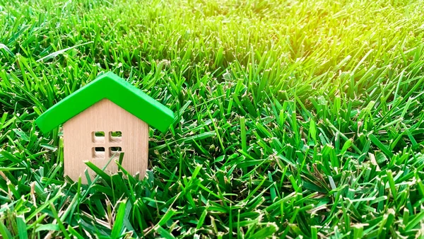 Miniature wooden house on grass. Real estate concept. Eco-friendly and energy efficient house. Buying a home outside the city. The urban downshift. Nature. Fresh air. Mortgage, loan. Green — Stock Photo, Image