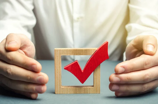 L'homme embrasse et protège le vote de la tique rouge. Le concept de protection contre la fraude et de soutien à la légitimité de l'élection. Faire le bon choix, la bonne stratégie de croissance et la réussite commerciale . — Photo