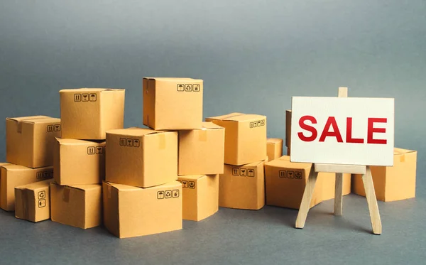 Many cardboard boxes and a sign stand with the word SALE. Sale of goods and products at attractive prices and promotions. big discounts on goods of the outgoing season. Attracting buyers. Shopping — Stock Photo, Image