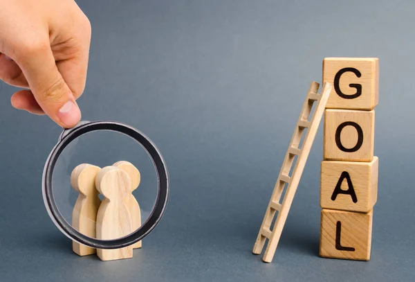 Lupa está mirando a tres personas están de pie cerca de la torre de cubos con la palabra objetivo. Evaluación de opciones y medios para conquistar la cumbre y lograr el objetivo. cooperación y trabajo en equipo — Foto de Stock