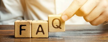 Businessman puts wooden blocks with the word FAQ (frequently asked questions). Collection of frequently asked questions on any topic and answers to them. Instructions and rules on Internet sites clipart