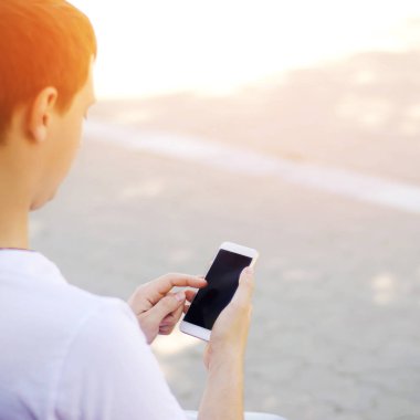 adam bir hareket eden smartphone tutarak ve ekrana bakarak. telefon bağımlılığı, sosyal ağlar. Internet üzerinde çalışma. mesajı yazın. güneşli bir gün. yakın çekim, metin için yer