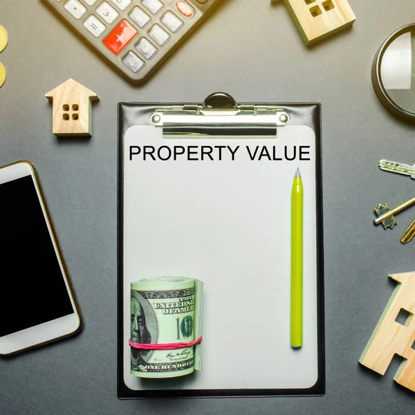 Table with wooden houses, calculator, coins, magnifying glass with the word Property value. The contract for real estate appraisal. Rate the property. Valuation house. Appraisal Services. Flat lay — Stock Photo, Image