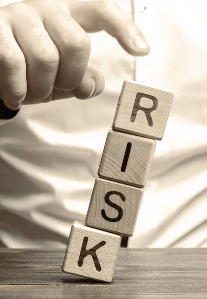 男はリスクという言葉でブロックを削除します。リスクを減らすという考え方。保険、安定支援。ビジネス上の利益の法的保護。金融枕。有利な投資環境. — ストック写真