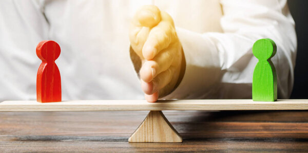 Деревянные фигуры людей на весах и посредник / арбитр. Разрешение конфликтных ситуаций и споров. Заключения о мирном разрешении споров. Конфликт интересов. Деловые противники
