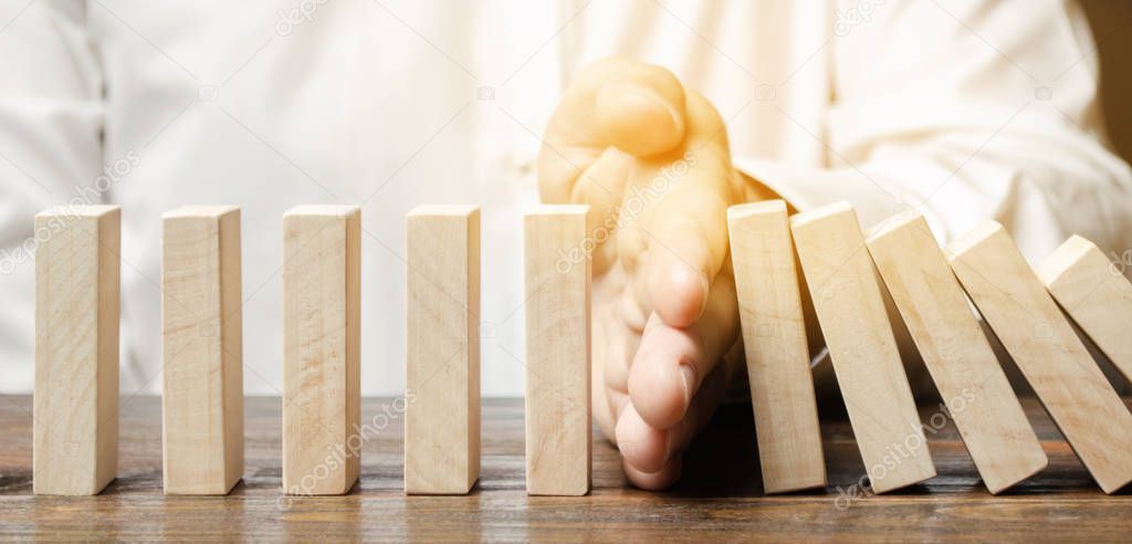Businessman stops domino falling. Risk management concept. Successful strong business and problem solving. Reliable leader. Stop the destructive processes. Strategy development. Debt restructuring