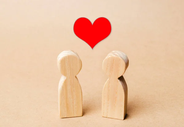 Miniatuur houten figuren van mensen en een rood hart erboven. Concept van liefde, romantische relatie. Medeleven. Een liefdevol koppel en romantiek. Geluk — Stockfoto