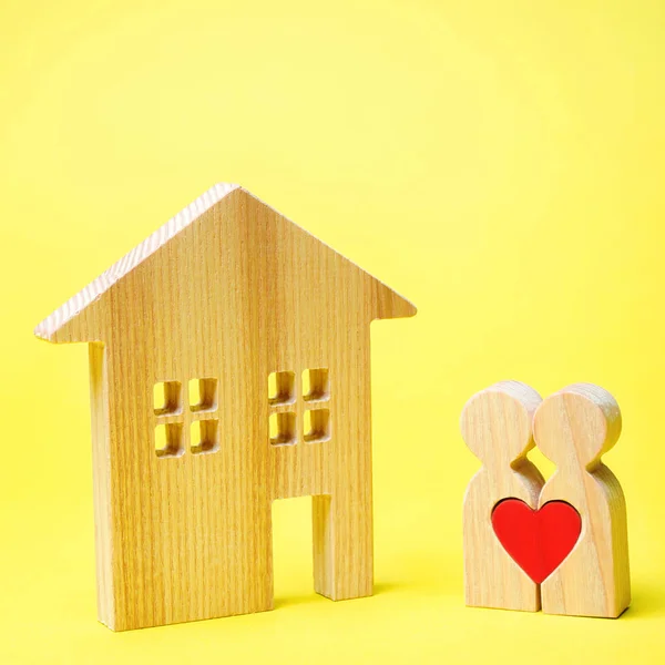 Un par de amantes están de pie cerca de la casa de madera. Día de San Valentín. Vivienda asequible para familias jóvenes. Propiedad de alquiler. Hipoteca y préstamo. El concepto de encontrar un apartamento o casa — Foto de Stock