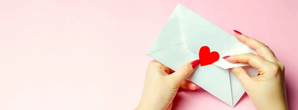 빨간 하트로 봉투를 들고 있는 암컷입니다. 발렌틴 데이 컨셉이야. 사랑하는 사람에게 보내는 사랑의 편지. 발렌타인 카드 축하 합니다. 사랑 고백. 위에서 본 광경. 편평 한 침대 — 스톡 사진