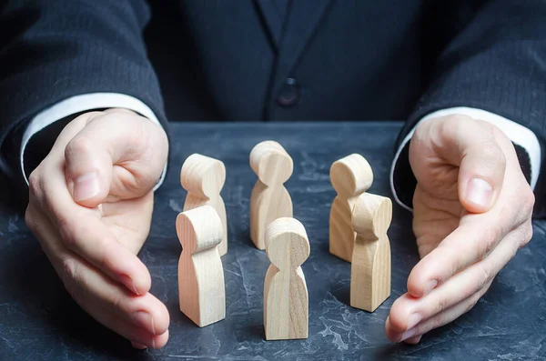 Businessman guards a circle of people with his hands. Team insurance. Preservation protection of company, ensuring safety of society. Legal services. Patronage, team building. Leader and leadership. — Stock Photo, Image