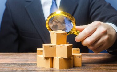 İş adamı büyüteçle kutuları inceliyor. Pazarlama satış promosyon stratejisi. Ticari piyasa yapısı araştırması, boş hedef kitleleri bulmak. Kalite denetimi ve standartlar