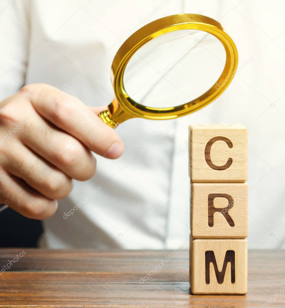 Wooden blocks with the word CRM (Customer Relationship Management) and businessman. Automation strategies for interacting with clients. Increase sales, optimize marketing. Selective focus