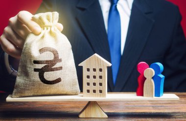Adam Ukraynalı Hryvnia para çantasını ve evi aile terazisine koyuyor. Sosyal yardım aileleri ve işgal altındaki bölgelerden gelen mülteciler konut ve maddi destekle. savunmasız gruplar