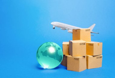 Mavi küre, karton kutular ve nakliye uçağı. Uluslararası dünya ticareti. Mal teslimatı, nakliye. Nakliye trafiğini içeri aktar. Piyasaların küreselleşmesi. Teslimat süresini azaltmak için hava ulaşımını kullanıyor..