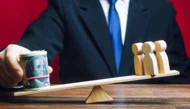 Bir adam teraziye bir tomar dolar koyar ve insanlardan ağır basar. Vergi mükellefleri konsepti. Personel uzmanları için iyi maaş. Yatırımlar, mevduatlar. Sosyal proje finansmanı. İnsan kaçakçılığı