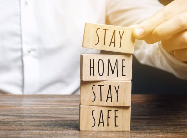 Adam ahşap blokları kelimelerin olduğu yere koyar. Evde kal. Koronavirüs enfeksiyonunu önleme kavramı. Kendini izole etme ve karantina. COVID-19, Ncov