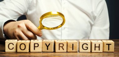 İş adamı, telif hakkı sözcüğünün üzerine tahta bloklar koyar. Patenti. Telif hakkı koruması. Marka ve patent. Çevrimiçi korsanlıkla mücadele.
