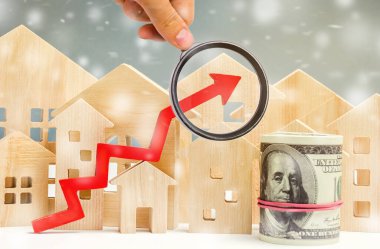 Minyatür ahşap evler ve kar taneli oklar. Yüksek konut talebi kavramı. Kışın gayrimenkul yatırımları. İpotek faiz oranları. Pahalı bir bedel. Noel pazarı