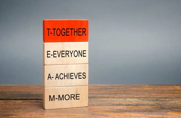 Wooden blocks with the word Together, Everyone, Achieves, More. Teamwork and team concept. Community, support, partnership. Achieving a common goal. Cooperation and business strategy