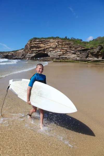 Jovem deixa o surf carregando sua prancha — Fotografia de Stock