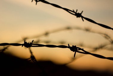 Günbatımı arkasında dikenli tel, askeri uzay.