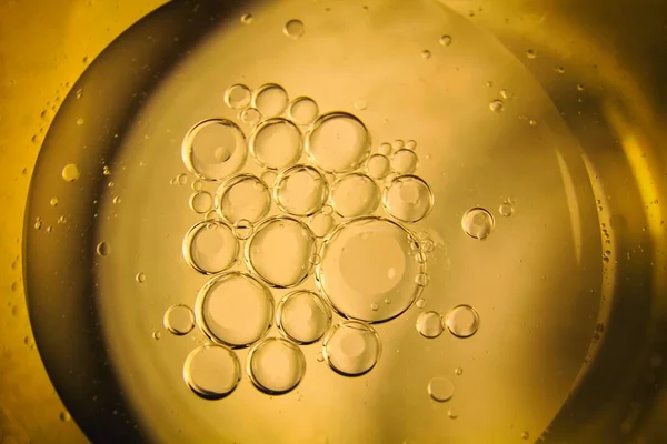 Yellow and orange bubbles and drops of oil in water, olive oil kitchen background for cooking.