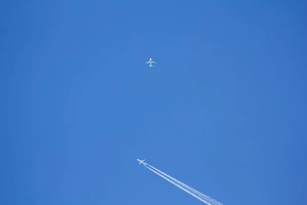 A flying plane on a blue sky, a condensation trace in the sky.