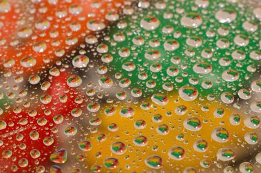 Cam, renkli arka plan üzerinde su damlaları.
