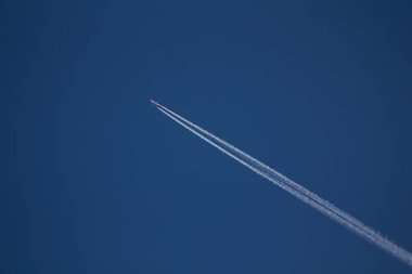 Mavi bir gökyüzü, gökyüzü bir yoğunlaşma izleme üzerinde uçan bir uçak.