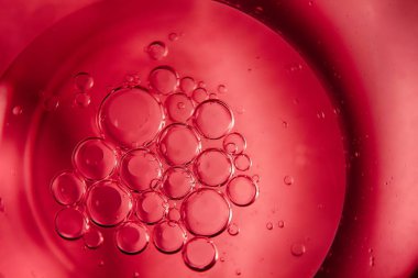 Kırmızı bir arka plan, petrol kabarcıklar ve damla su.