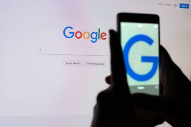 Bir kişi Google arama dizisi ile monitör ekranının bir resmini çeker.
