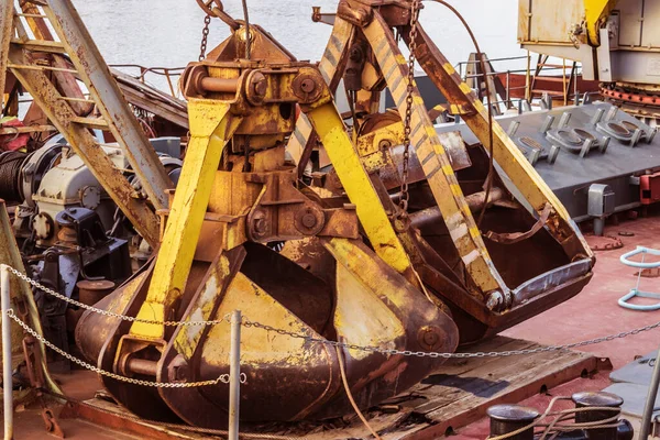 Oude roestige graafmachine emmer liggend op het dek van een rivierschip — Stockfoto