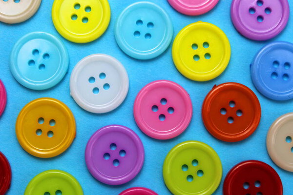 Texture of multi-colored buttons laid out on a blue surface