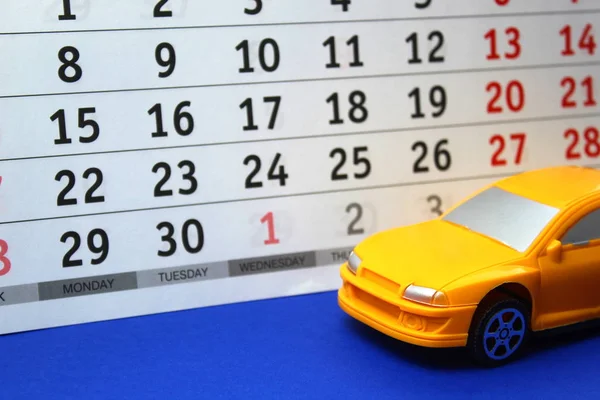 Yellow toy car on a calendar background