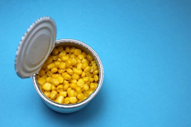 Jar with canned yellow corn on a blue background