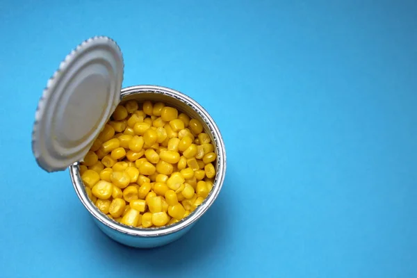 Jar with canned yellow corn on a blue background