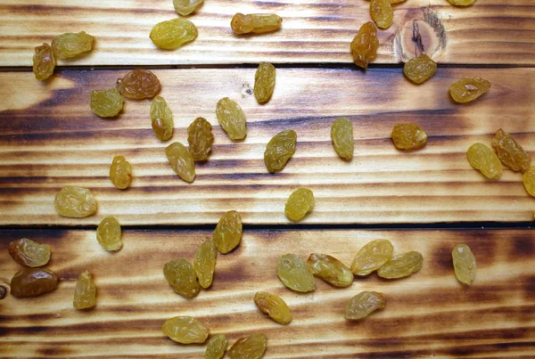 Texture yellow raisins scattered on a wooden surface