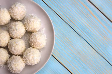 Hindistan cevizi taneleriyle yuvarlak şekerler bir tabakta yatıyor.