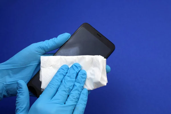 Tıbbi eldivenli eller telefonu dezenfekte eder.
