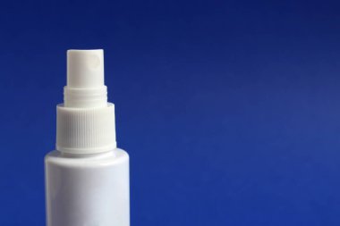 El spreyi, mavi arka planda dezenfeksiyon için beyaz tüp.