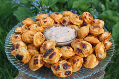 Izgarada kızarmış hamur köftesi soslu bir tabakta yatıyor.