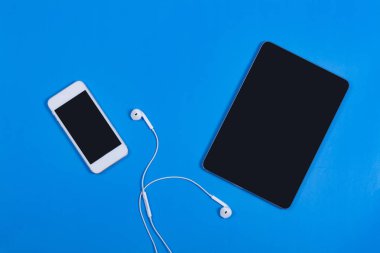 Mavi arka planda siyah tabletli beyaz telefon