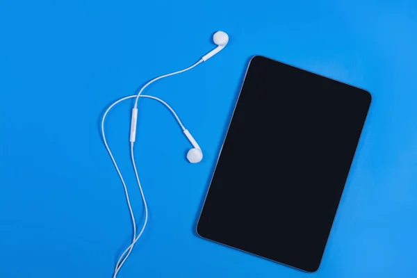 Tablet Mini hitam dengan headphone pada latar belakang biru — Stok Foto