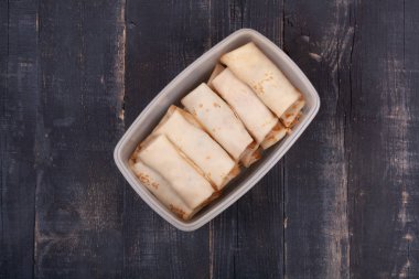 Ahşap bir masada plastik bir kasede bir sürü pişmiş krep.